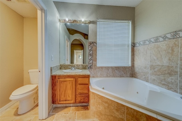 bathroom featuring vanity, a relaxing tiled tub, and toilet