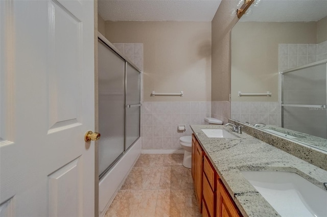 full bathroom featuring tile patterned floors, bath / shower combo with glass door, vanity, a textured ceiling, and toilet