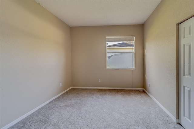 spare room featuring light carpet and a textured ceiling