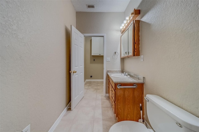 bathroom with tile patterned floors, vanity, toilet, and a textured ceiling