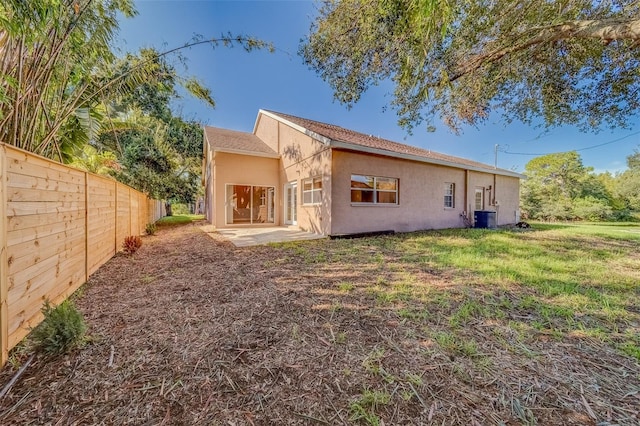 rear view of property featuring central AC and a yard