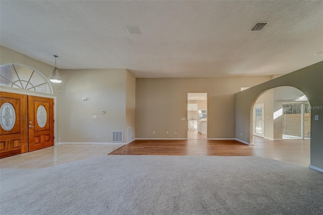 entrance foyer with light colored carpet and a textured ceiling