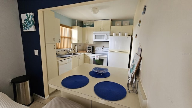 kitchen with light tile patterned floors, cream cabinets, sink, and white appliances