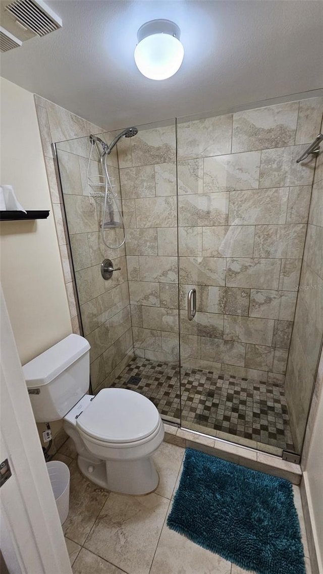 bathroom featuring toilet, an enclosed shower, and tile patterned floors