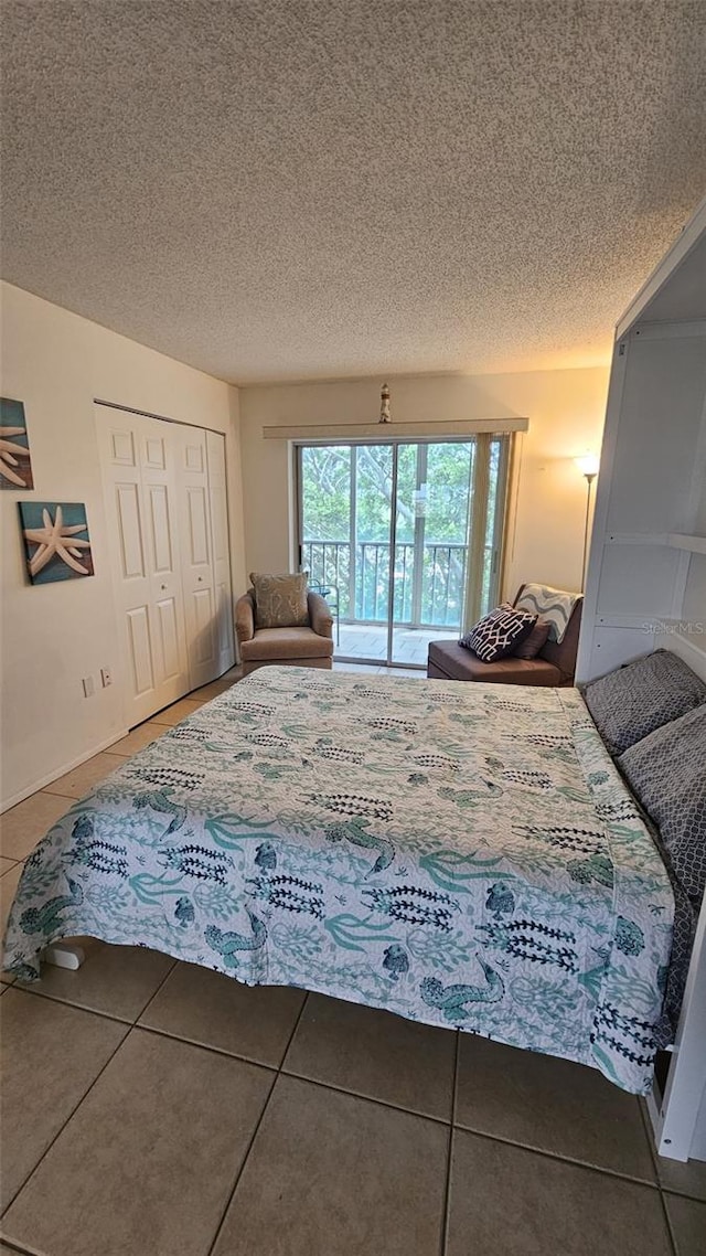 tiled bedroom with a closet, a textured ceiling, and access to outside