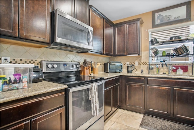 kitchen featuring dark brown cabinetry, appliances with stainless steel finishes, backsplash, and light tile patterned floors