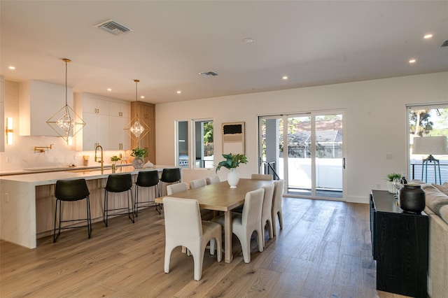 dining area with light hardwood / wood-style flooring, a chandelier, and sink