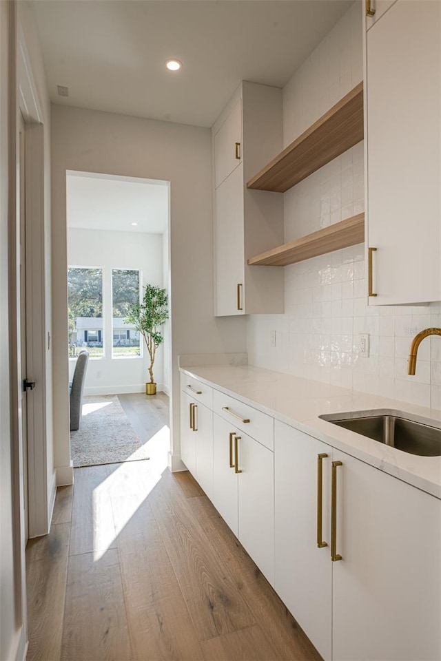 kitchen featuring tasteful backsplash, sink, white cabinets, and light hardwood / wood-style flooring