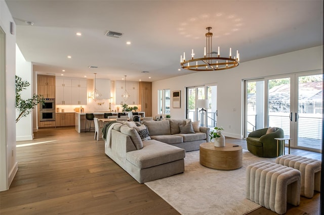 living room featuring french doors, light hardwood / wood-style flooring, and a chandelier