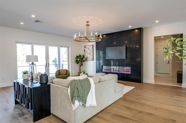 living room featuring a large fireplace, hardwood / wood-style flooring, and an inviting chandelier