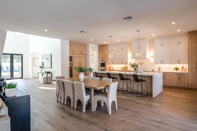 dining room with french doors, light wood-type flooring, and sink