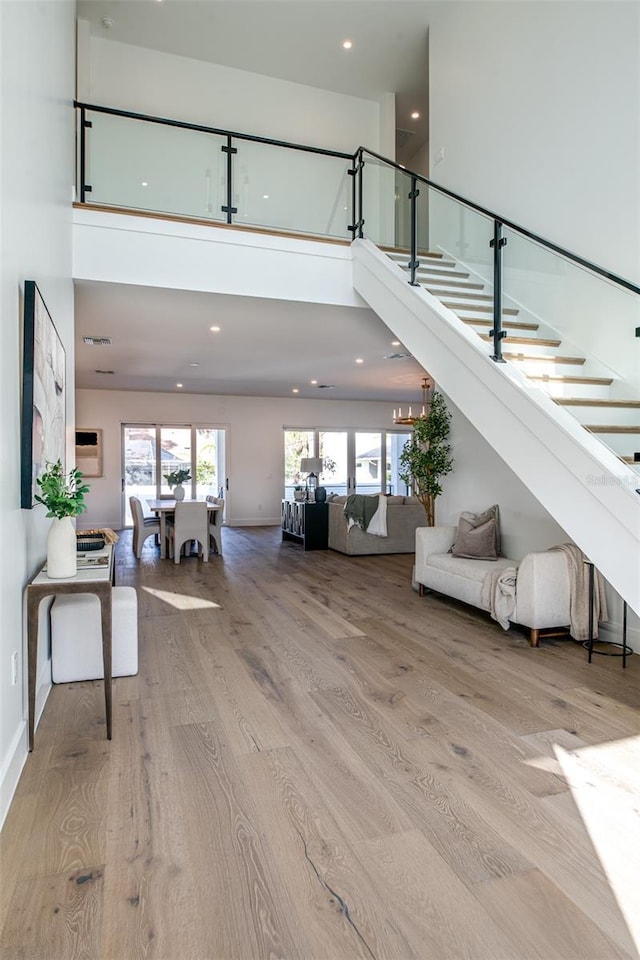 stairs with wood-type flooring and a high ceiling