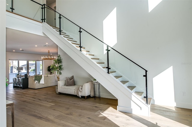 stairway featuring hardwood / wood-style flooring, a towering ceiling, and a chandelier