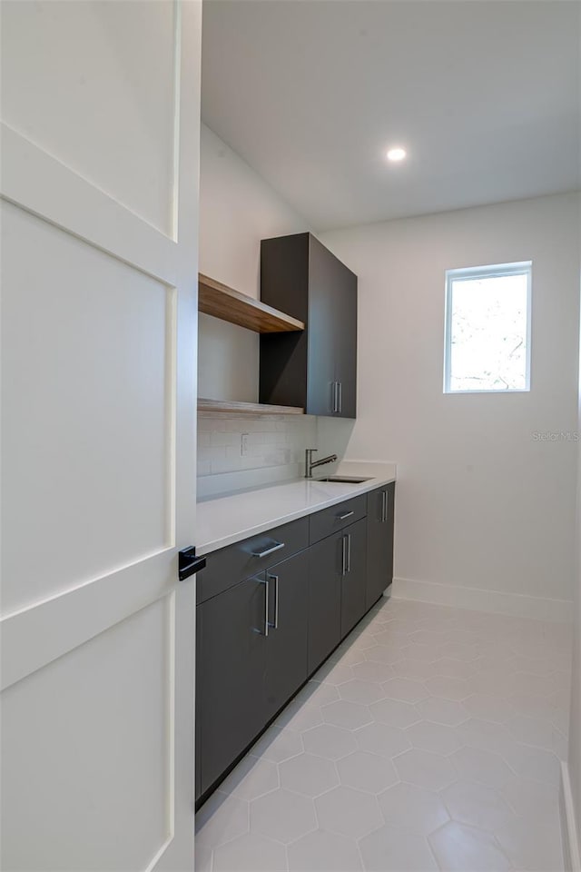 kitchen featuring light tile patterned floors, backsplash, and sink