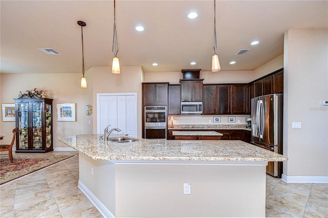 kitchen featuring an island with sink, stainless steel appliances, and light stone counters