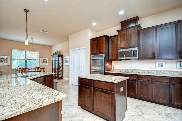 kitchen with appliances with stainless steel finishes, a center island, decorative light fixtures, dark brown cabinetry, and sink