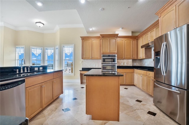 kitchen featuring stainless steel appliances, backsplash, a kitchen island, crown molding, and sink