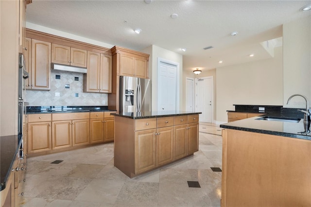 kitchen with appliances with stainless steel finishes, tasteful backsplash, dark stone countertops, a kitchen island, and sink