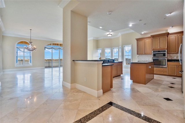 kitchen with a wealth of natural light, a chandelier, backsplash, and a center island