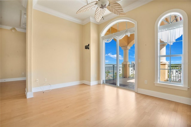 empty room featuring a wealth of natural light, crown molding, and light hardwood / wood-style flooring