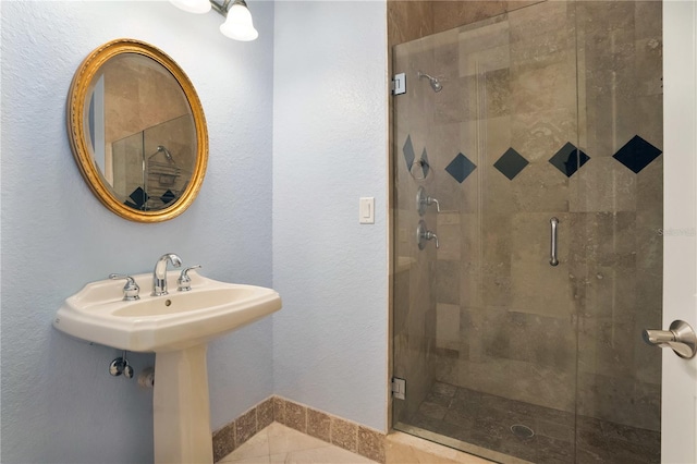 bathroom with tile patterned floors, a shower with shower door, and sink