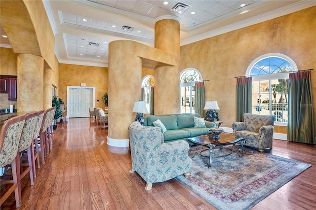 living room with a towering ceiling, plenty of natural light, and ornamental molding