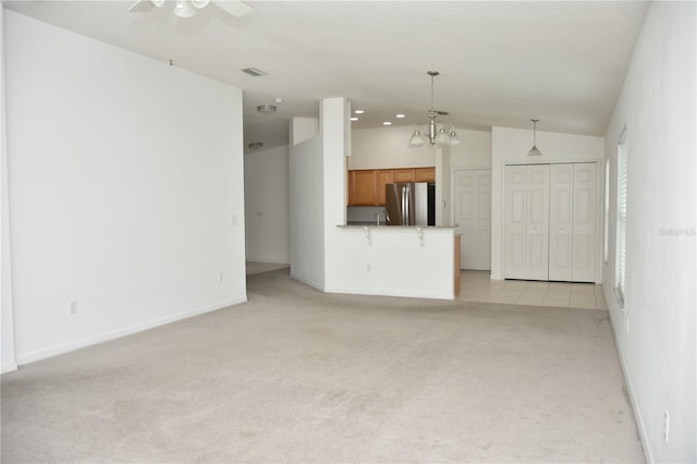 unfurnished living room with sink, vaulted ceiling, light carpet, and ceiling fan with notable chandelier