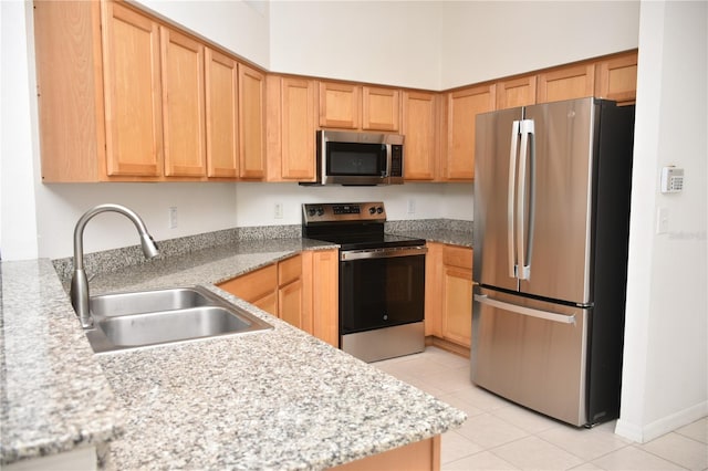 kitchen featuring light stone countertops, light tile patterned flooring, appliances with stainless steel finishes, and sink