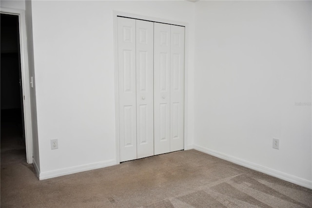 unfurnished bedroom with light carpet and a closet