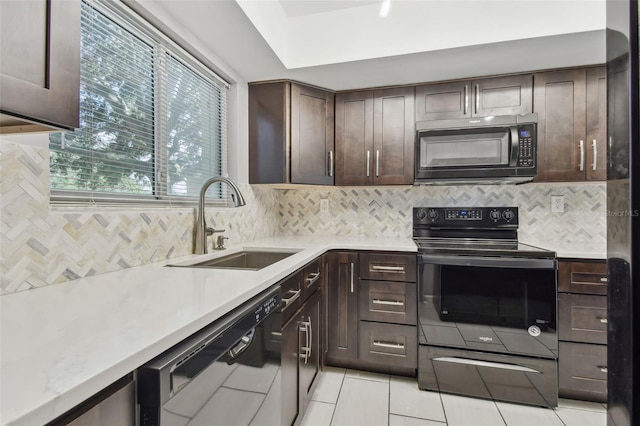 kitchen featuring tasteful backsplash, dark brown cabinetry, sink, black appliances, and light tile patterned floors