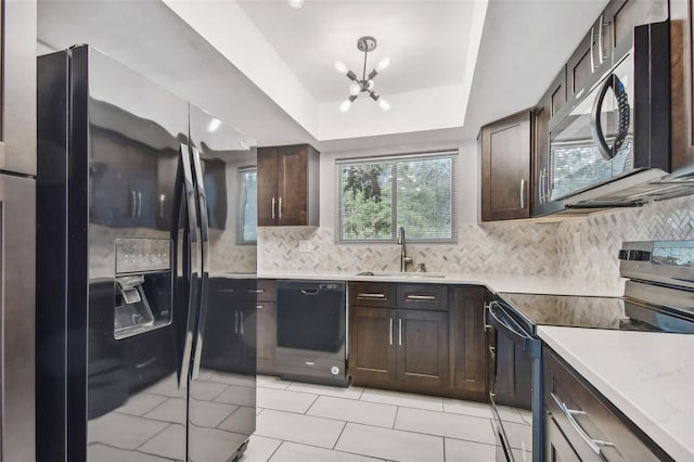 kitchen featuring tasteful backsplash, black appliances, an inviting chandelier, and a raised ceiling