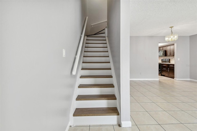 stairs with tile patterned flooring, an inviting chandelier, and a textured ceiling