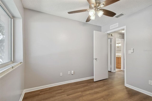 unfurnished bedroom featuring dark wood-type flooring, a textured ceiling, and ceiling fan