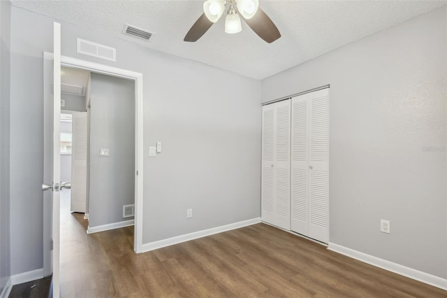 unfurnished bedroom featuring ceiling fan, a textured ceiling, a closet, and dark wood-type flooring