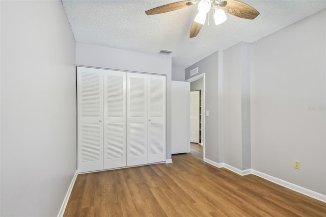 unfurnished bedroom with light wood-type flooring, ceiling fan, a closet, and a textured ceiling