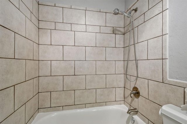 bathroom featuring tiled shower / bath and toilet