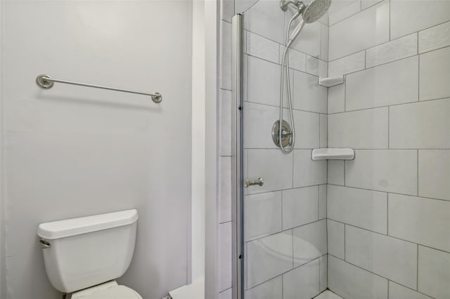 bathroom featuring toilet and a shower with shower door