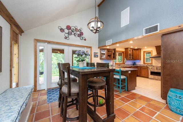 dining room with light tile patterned floors, sink, high vaulted ceiling, and a chandelier