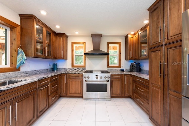 kitchen featuring light stone countertops, sink, wall chimney exhaust hood, and high end stainless steel range oven