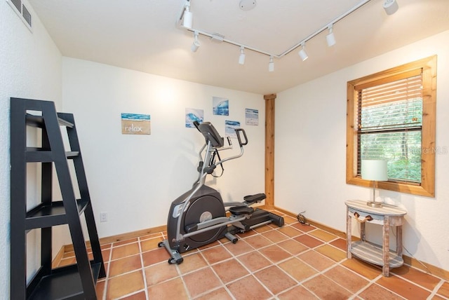 exercise room featuring rail lighting and tile patterned floors