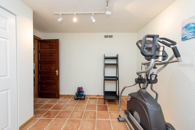 exercise area featuring tile patterned flooring and track lighting