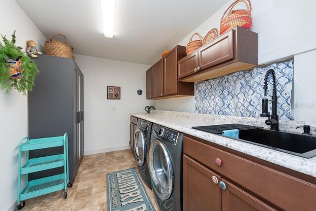 clothes washing area featuring washer and clothes dryer, cabinets, and sink