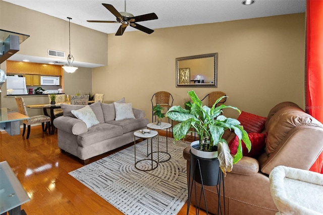 living room with a textured ceiling, ceiling fan, and dark wood-type flooring