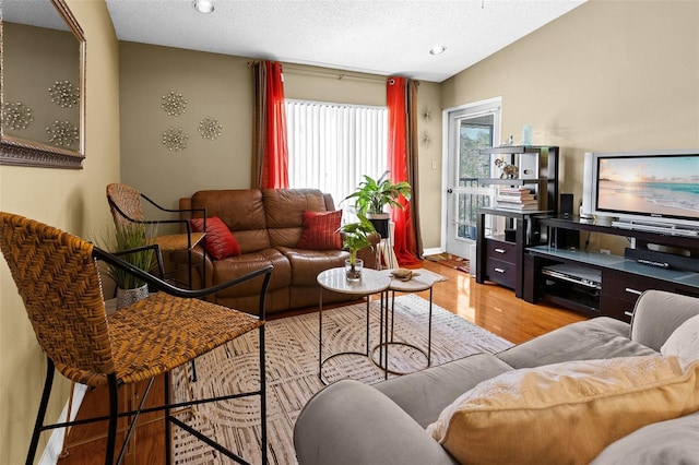 living room featuring light hardwood / wood-style flooring, lofted ceiling, and a textured ceiling