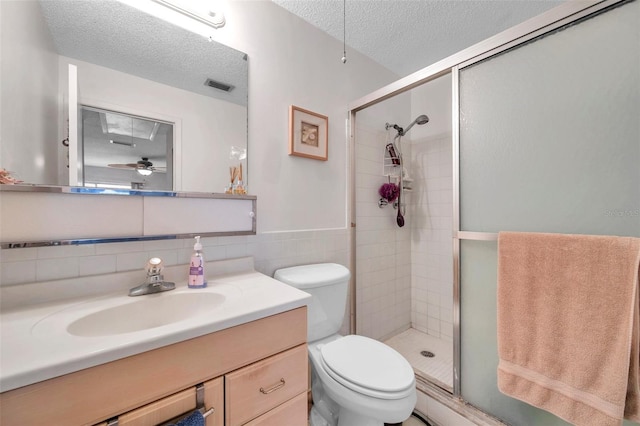 bathroom with toilet, vanity, an enclosed shower, a textured ceiling, and ceiling fan