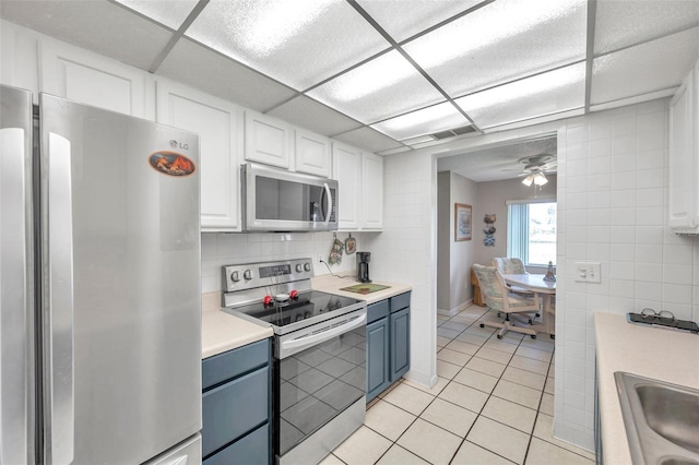 kitchen with ceiling fan, light tile patterned floors, white cabinetry, blue cabinetry, and stainless steel appliances