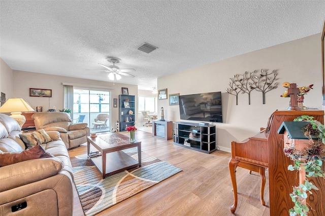 living room with light hardwood / wood-style floors, a textured ceiling, and ceiling fan