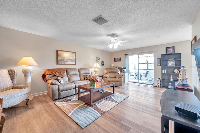 living room featuring a textured ceiling, light wood-type flooring, and ceiling fan