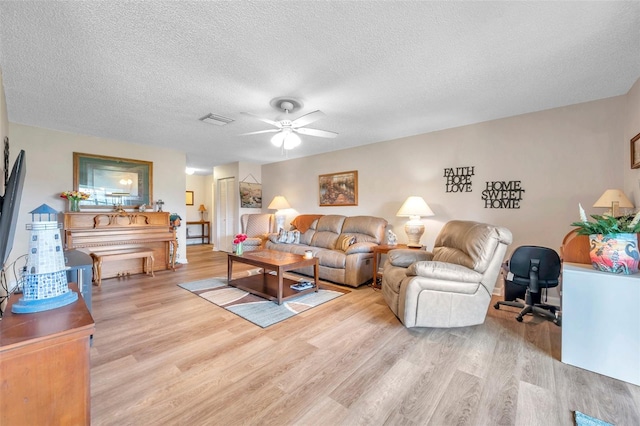 living room with a textured ceiling, light wood-type flooring, and ceiling fan