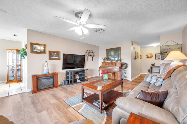 living room with ceiling fan, wood-type flooring, and a textured ceiling